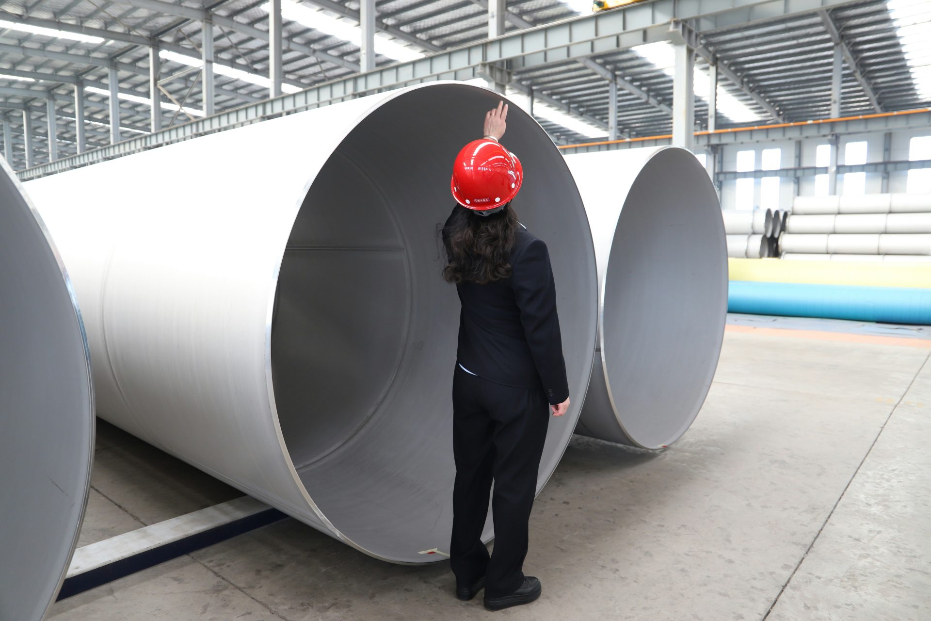 Ein Arbeiter inspiziert große Metallrohre in einer Fabrik.